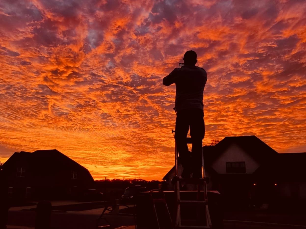 Sky's the Limit craftsman working at sunset — silhouette against a fiery Tennessee sky
